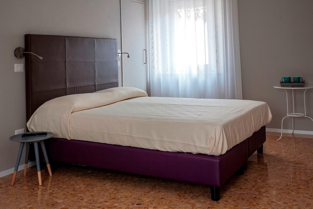 A bedroom with a bed, a small table, and a curtain.