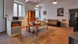 Un coin repas avec une table et des chaises en bois, un meuble blanc contenant un four à micro-ondes et un meuble en bois avec des tiroirs.