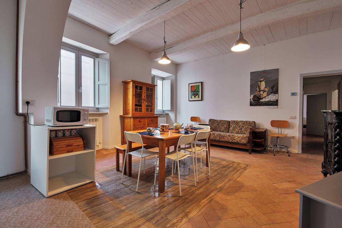 Un comedor con una mesa y sillas de madera, un mueble blanco con microondas y un mueble de madera con cajones.