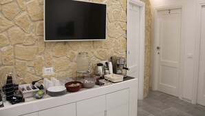 Una cocina con pared de piedra, un televisor de pantalla plana, una cafetera y una puerta con el número 2.
