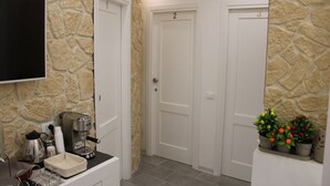 Un baño con pared de piedra, una cafetera, un lavamanos y una planta en maceta.
