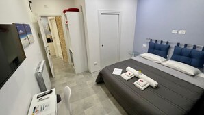Una habitación de hotel con una cama, un escritorio con ordenador, una silla y un televisor.