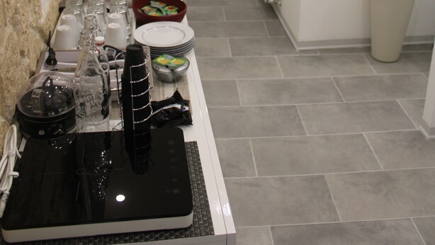 Un área de cocina con encimera, cafetera y distintos utensilios de cocina.