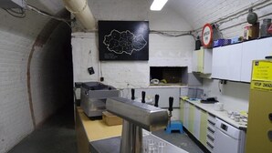 A kitchen with a stainless steel tap, a map on the wall, and a yellow caution sign.