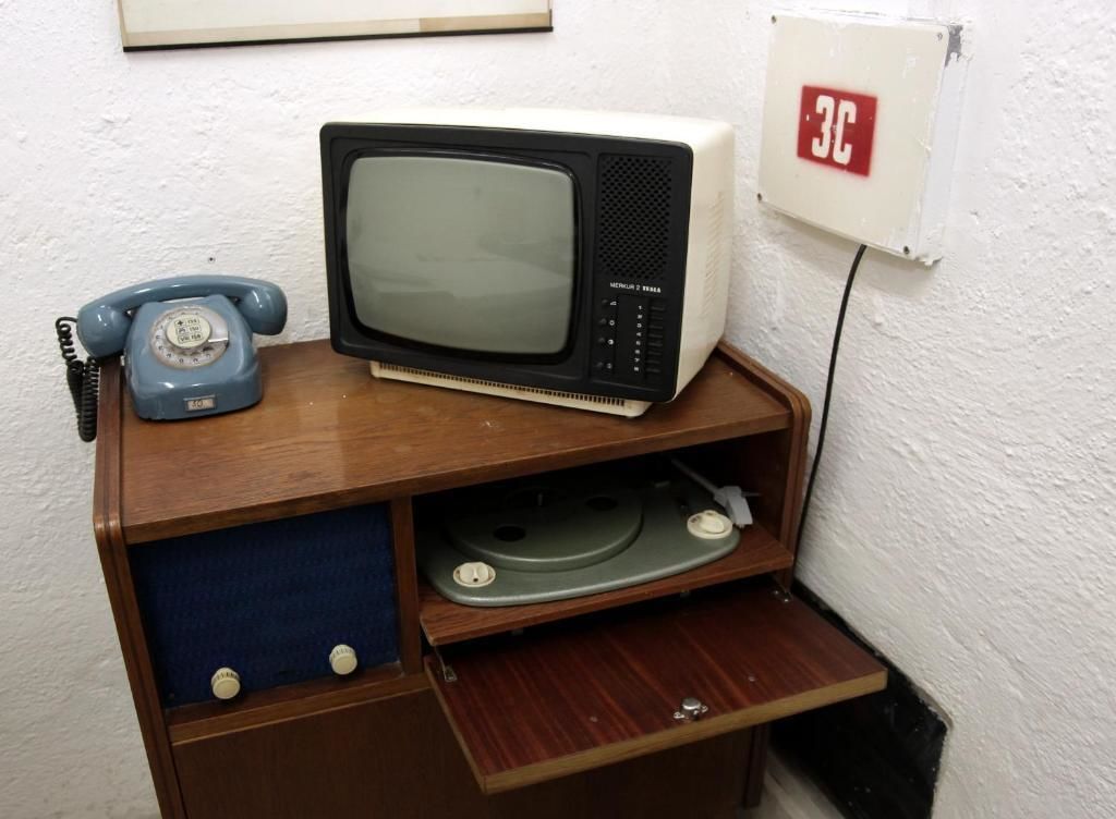 A wooden cabinet with a microwave, a rotary dial telephone, and a small shelf.