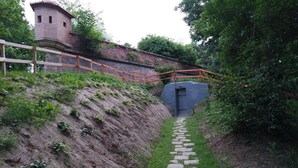A stone pathway leading to a brick tower, surrounded by greenery.