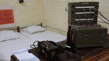 A room with a bed, a wooden dresser, and a vintage electronic device on top.
