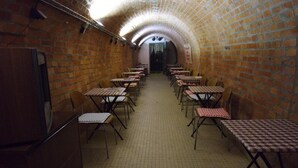 A brick-walled corridor with tables and chairs arranged for dining.
