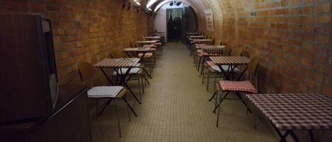 A brick-walled corridor with tables and chairs arranged for dining.