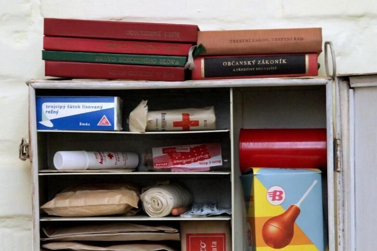 A storage cabinet with various items including books, medical supplies, and packaged goods.