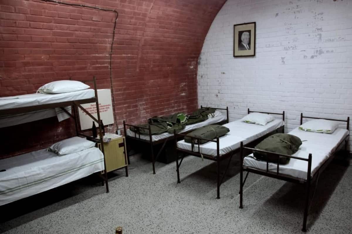 A dormitory room with bunk beds, a white brick wall, and a framed picture on the wall.