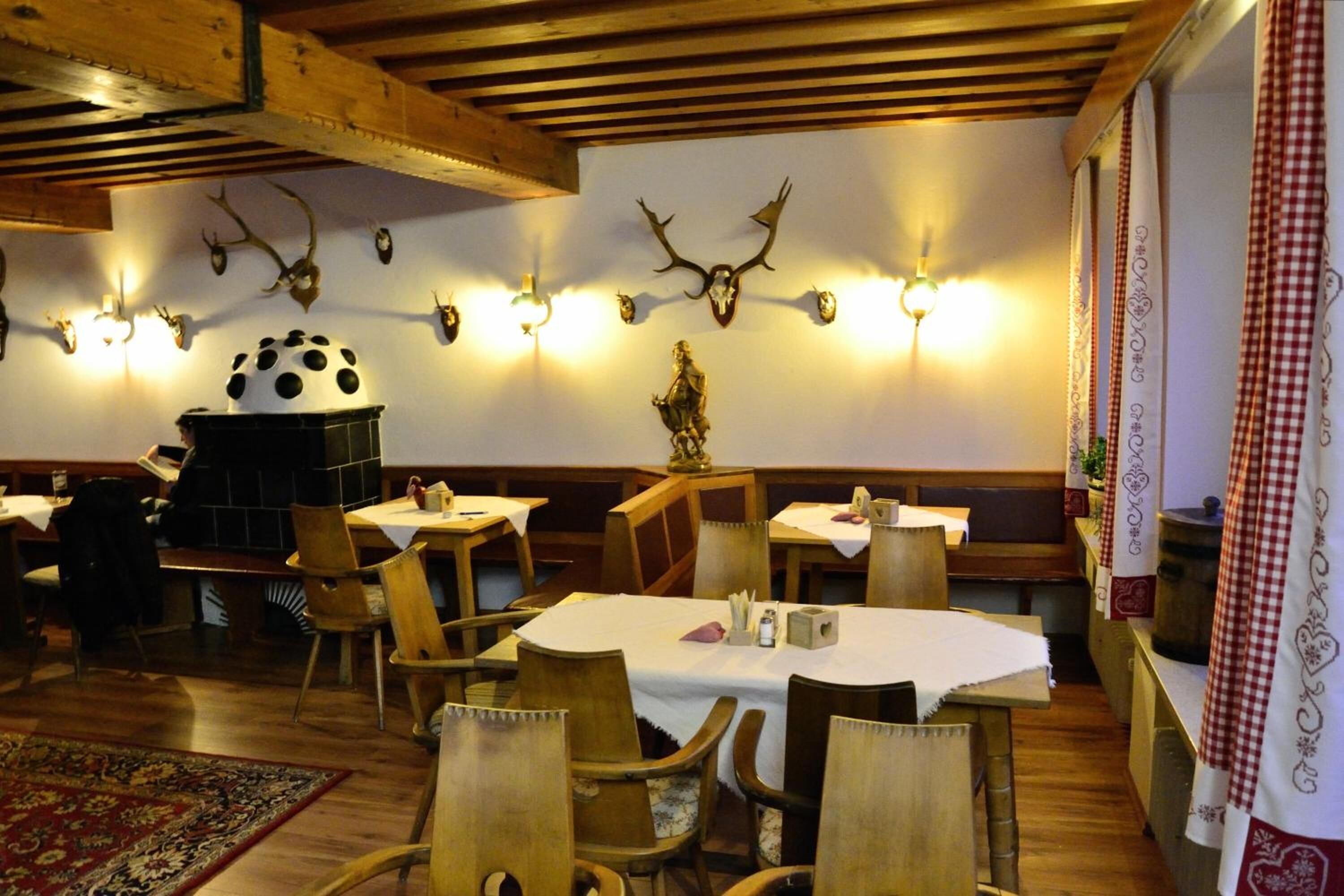 A restaurant with wooden furniture, a fireplace, and wall-mounted deer antlers.