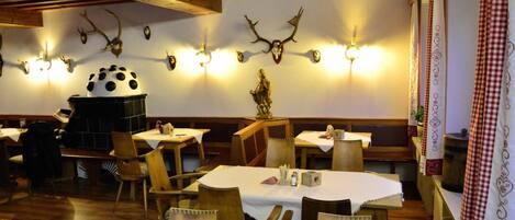 A restaurant with wooden furniture, a fireplace, and wall-mounted deer antlers.