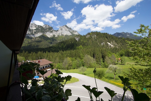 A mountain view from a balcony with a road leading to a building. - Alpenhotel Beslhof (Ramsau bei Berchtesgaden)