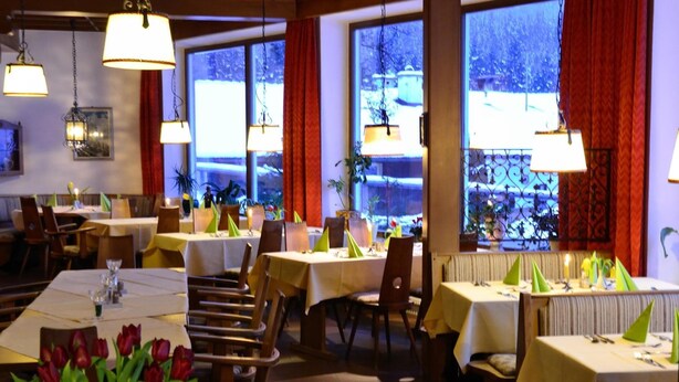Un restaurante con varias mesas, sillas y lámparas colgantes.