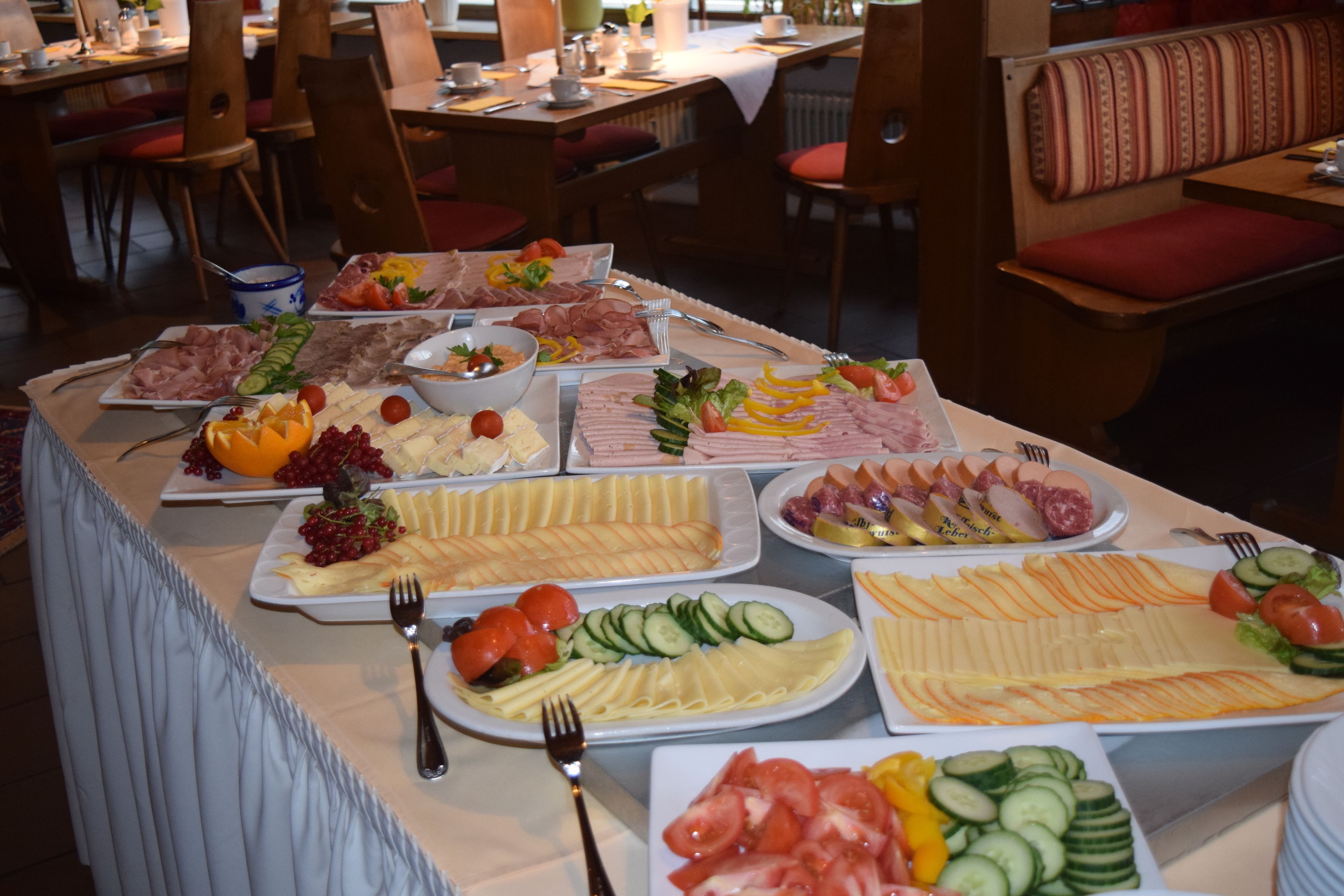 Un bufé con diversas opciones de comida, incluyendo carnes, quesos y verduras.