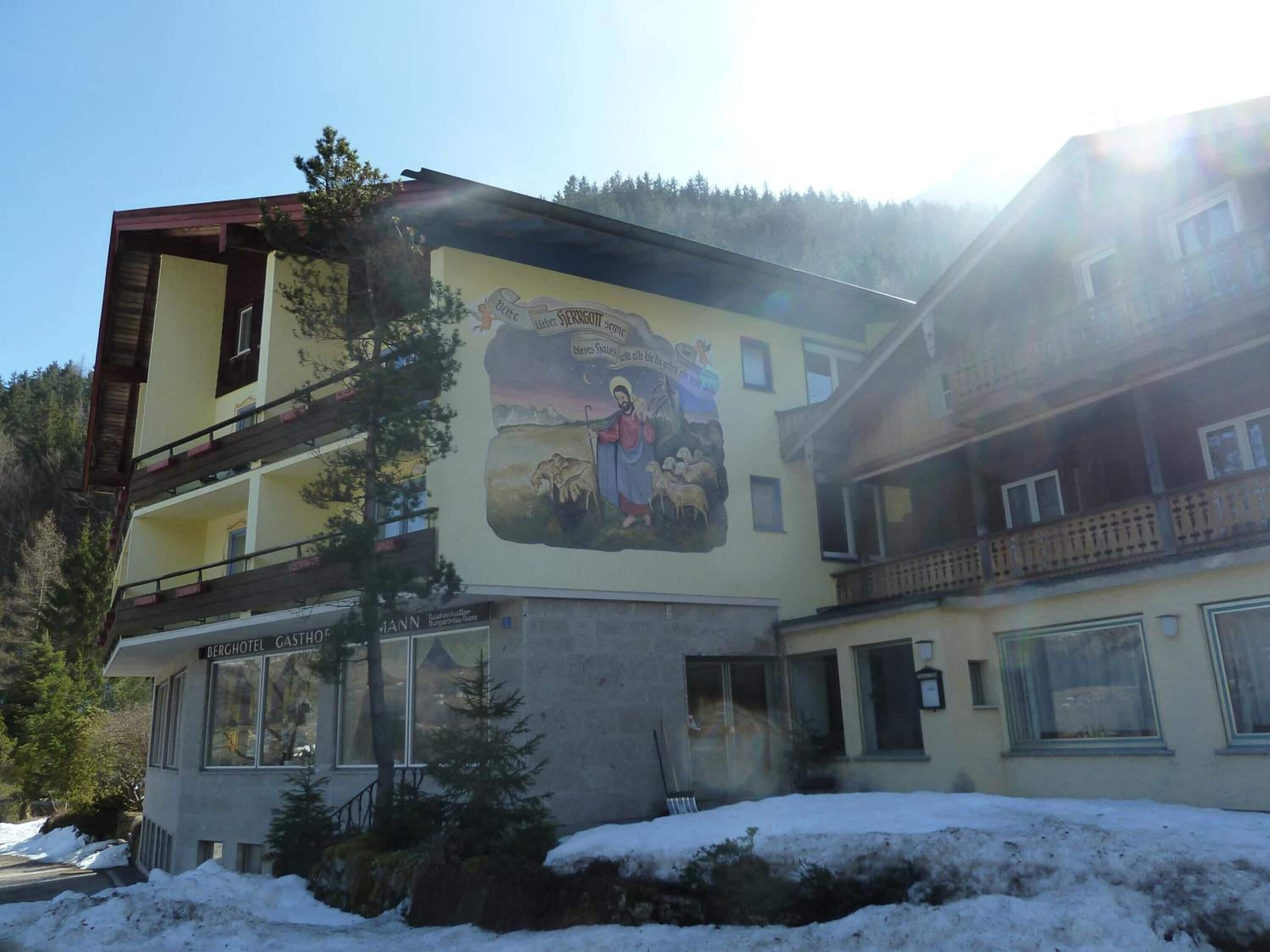 Ein Hotel mit Wandgemälde, das eine religiöse Szene zeigt, mit Balkon und verschneiter Landschaft.