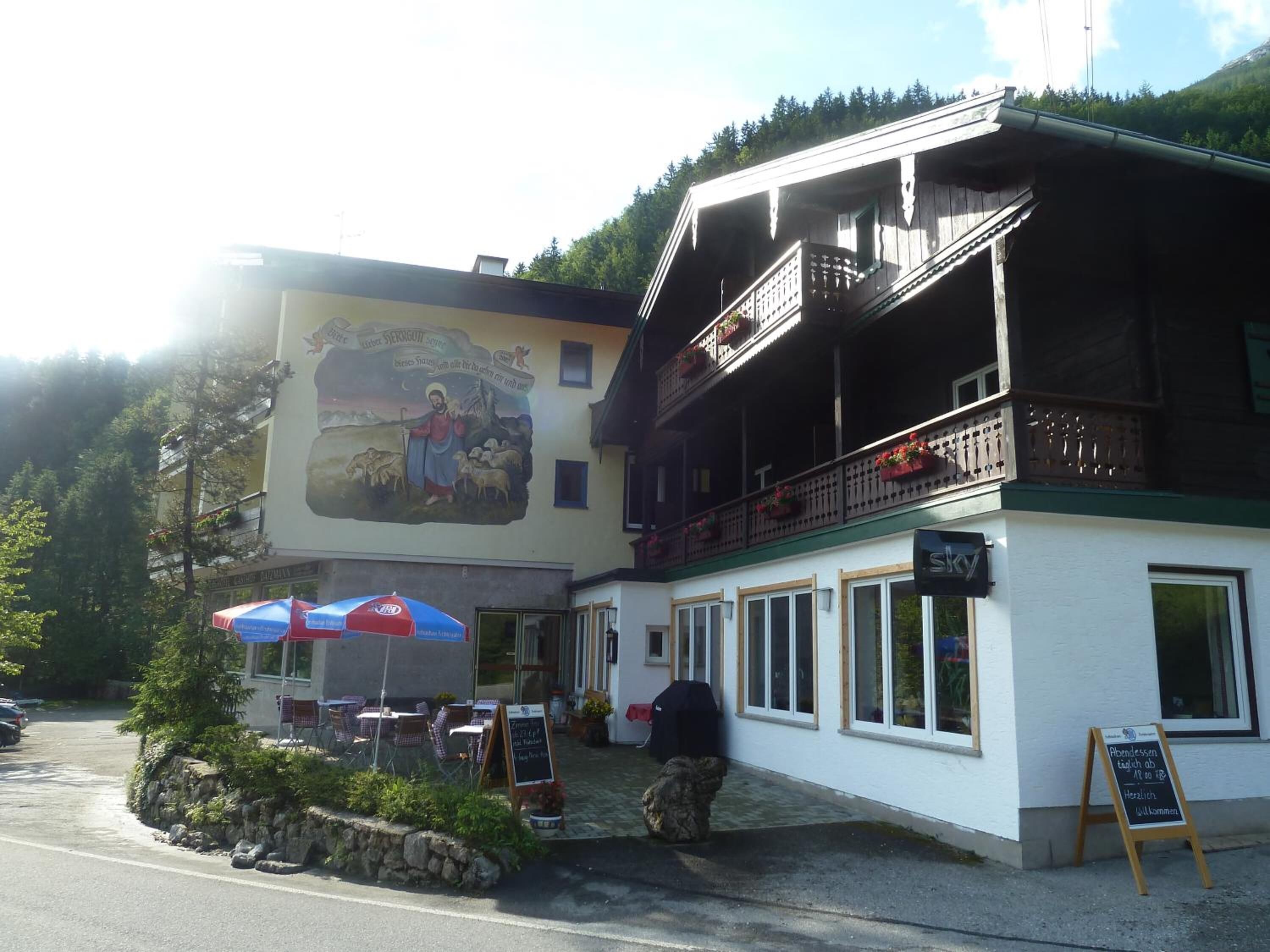 A building with a mural, outdoor seating, and a signboard.