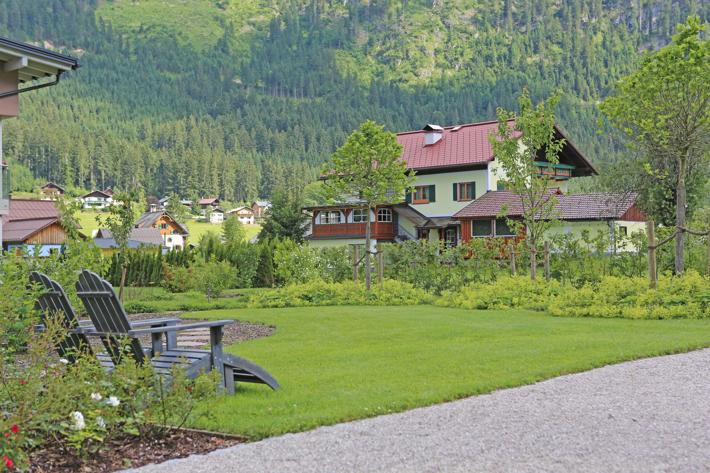 A residential area with houses, a grassy lawn, and a row of Adirondack chairs.