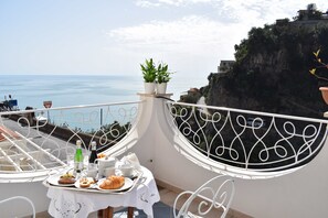 A balcony with a table set for breakfast overlooking a coastal view. - Villa Guarracino Amalfi (Amalfi)