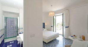 Ein Hotelzimmer mit Bad, Bett, Balkon und Frühstücksecke.