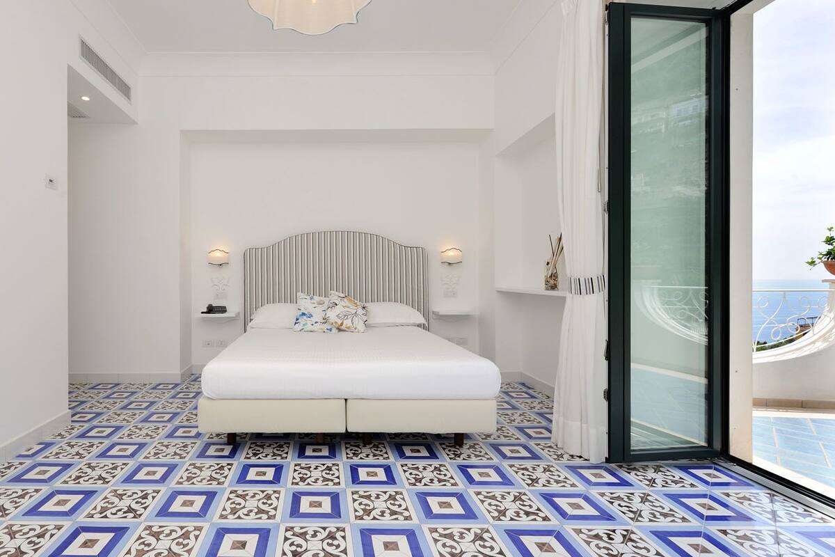 Une chambre à coucher avec un grand lit, une tête de lit à rayures et un sol à motifs.