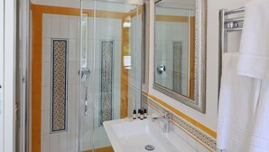 Une salle de bain avec une douche à parois de verre, un lavabo blanc et un grand miroir.