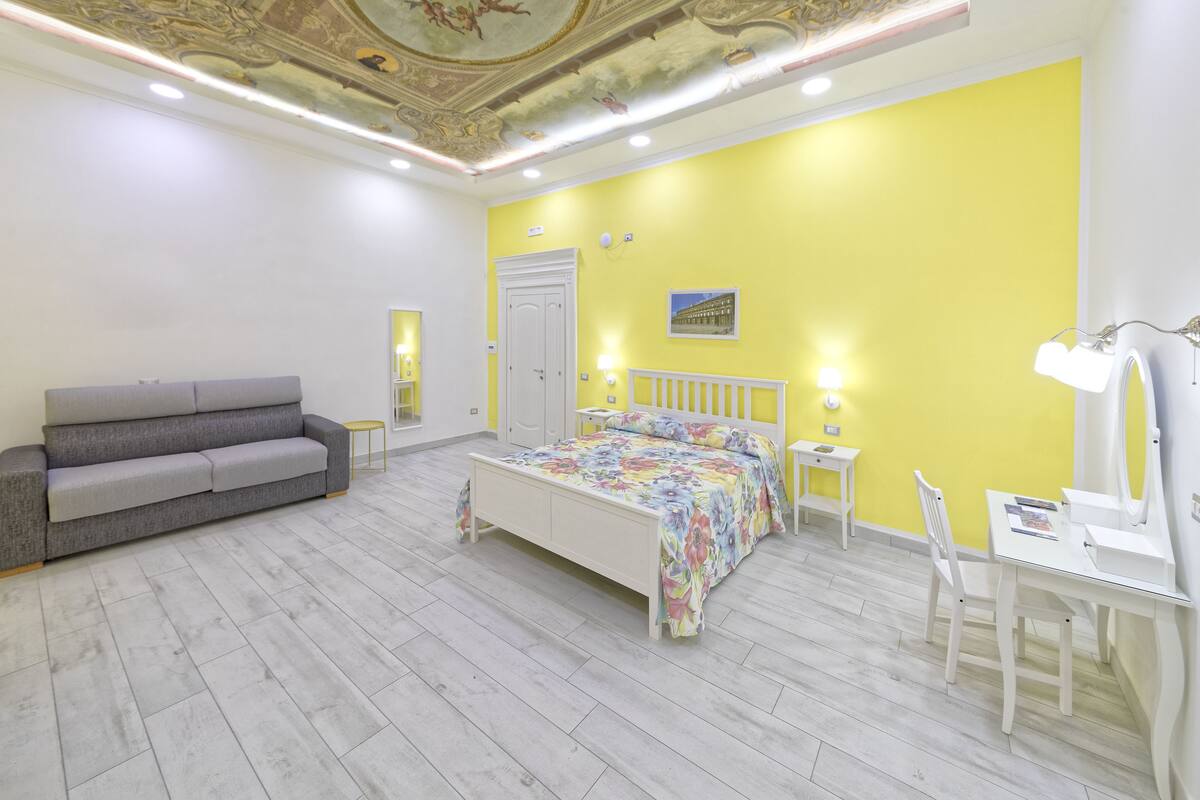 A bedroom with a bed, a sofa, a desk, and a chair.