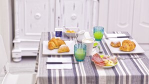 A breakfast setting with croissants, a plate of ham and cheese, and two glasses of green juice on a striped tablecloth. - B&B Rest a Napoli (Naples)