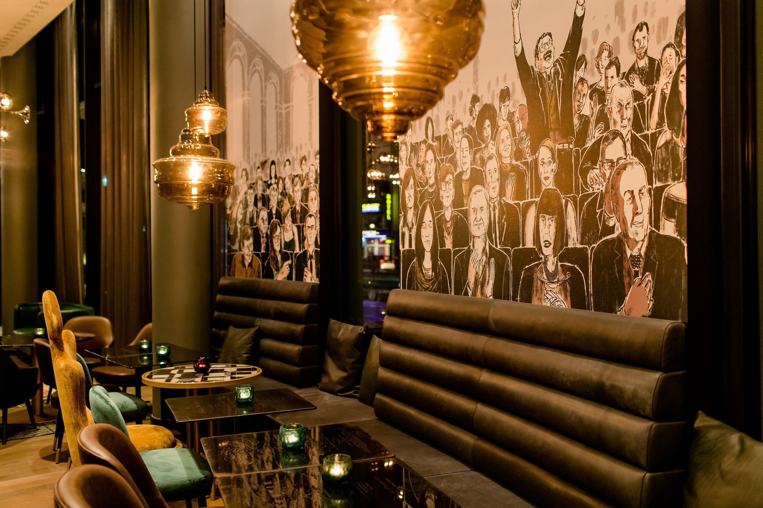 A modern lounge with leather seating, a chandelier, and a wall mural.