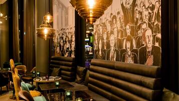 A modern lounge with leather seating, a chandelier, and a wall mural.
