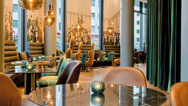 A modern restaurant interior with round tables, cushioned seating, and pendant lighting. - Motel One Bonn-Beethoven (Bonn)