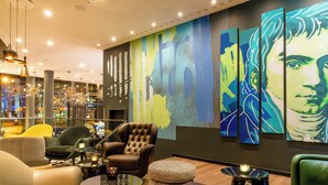 A modern lounge area with leather armchairs, a round coffee table, and a large abstract painting on the wall. - Motel One Bonn-Beethoven (Bonn)