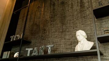 Una habitación con pared texturizada, un busto y estanterías con objetos metálicos.