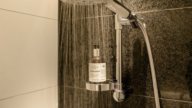 A shower with a handheld showerhead and a bottle of organic body mist. - Motel One Bonn-Beethoven (Bonn)