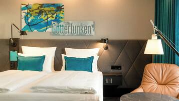 Ein Hotelzimmer mit Bett, Nachttisch, Lampe, Stuhl und einem Wandbild.