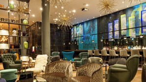 A modern interior with plush seating, a bar area, and a large digital display wall. - Motel One Bonn-Beethoven (Bonn)