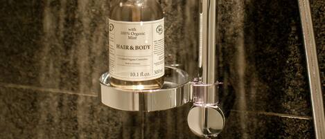 Un cabezal de ducha con una botella de champú para cabello y cuerpo.