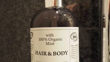 A bottle of hair and body product with a pump dispenser, labeled as containing 100% organic mint.