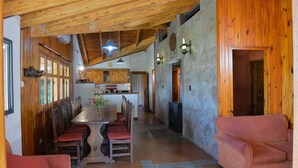 A spacious kitchen with wooden cabinets, a central island, and a dining area with chairs. - Entre Montañas y Rio (Cacheuta)
