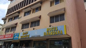 A multi-story building with a sign for 'Hotel Janardana' and 'Boarding & Lodging'. - Hotel Janardana (Udupi)