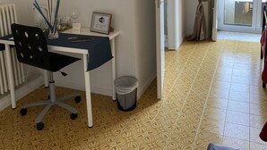 Habitación con escritorio, silla y un cuadro en la pared. Hay una puerta que da a un espacio al aire libre.