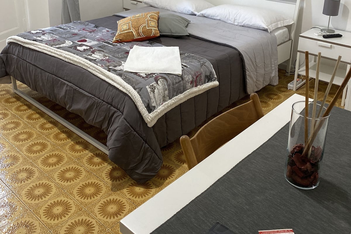 A neatly arranged hotel room with a bed, bedside tables, a desk, and a chair.