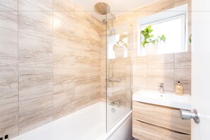 Ein modernes Badezimmer mit einer Duschkabine, einer weißen Badewanne und einem Holzbadezimmermöbel mit Spiegel.