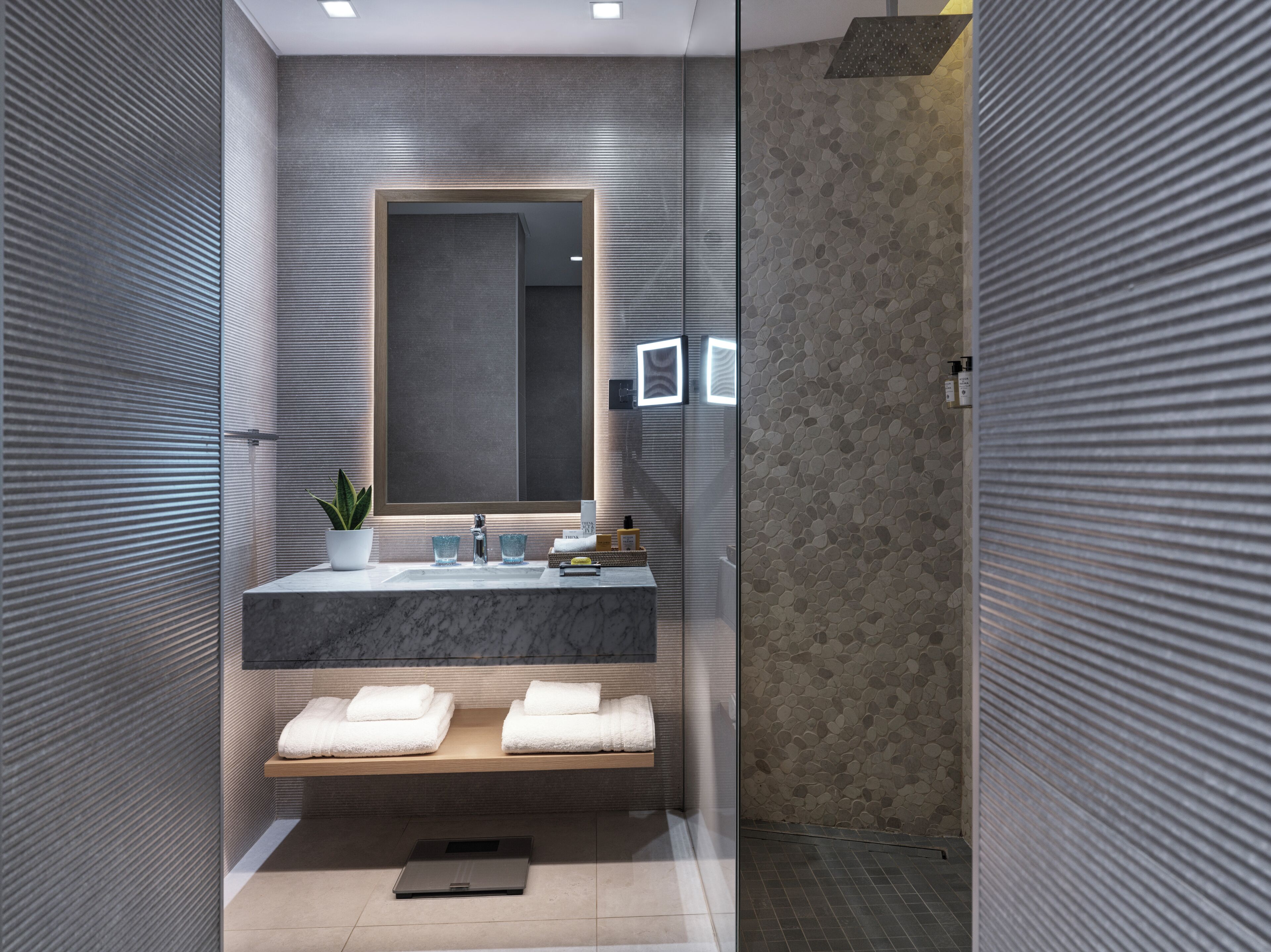 Une salle de bain moderne avec un lavabo en marbre, un grand miroir et un espace douche.