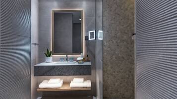 A modern bathroom with a marble sink, a large mirror, and a shower area.