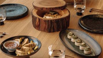 A dining table set with various dishes, including a bowl of dumplings, a plate of appetizers, and a wooden bowl with food.