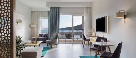 Een moderne hotelkamer met balkon, een bank, een eethoek en een televisie.