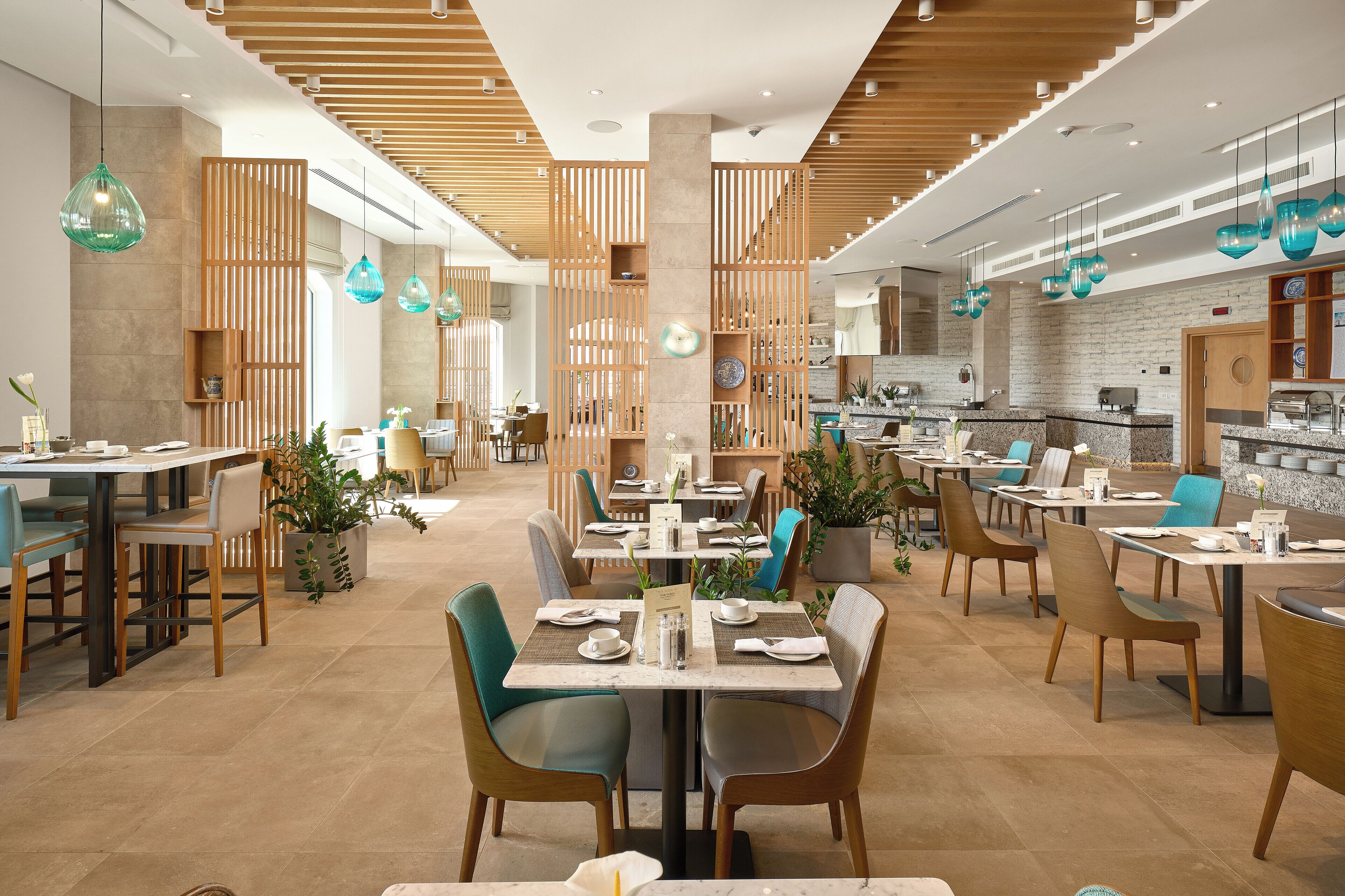 Un restaurant moderne avec des éléments décoratifs en bois, des chaises vertes et des luminaires suspendus.