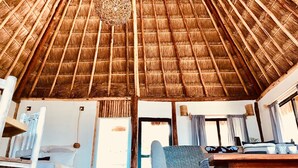 Una habitación con techo de paja, una cama, un sofá y una mesita.
